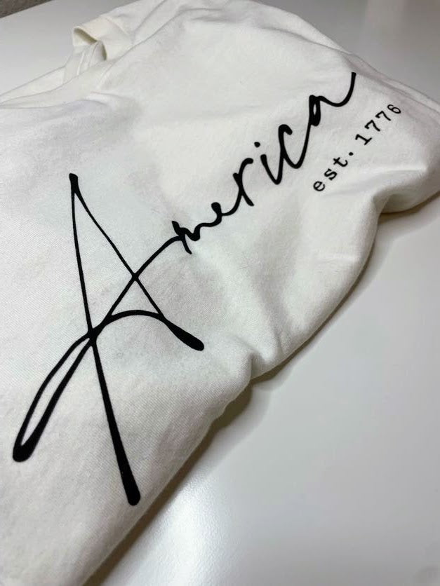 Show your patriotic spirit with our "AMERICA EST. 1776" T-shirt. This hand-screen printed graphic tee proudly displays its message on a high-quality 100% cotton fabric, ensuring both style and comfort.