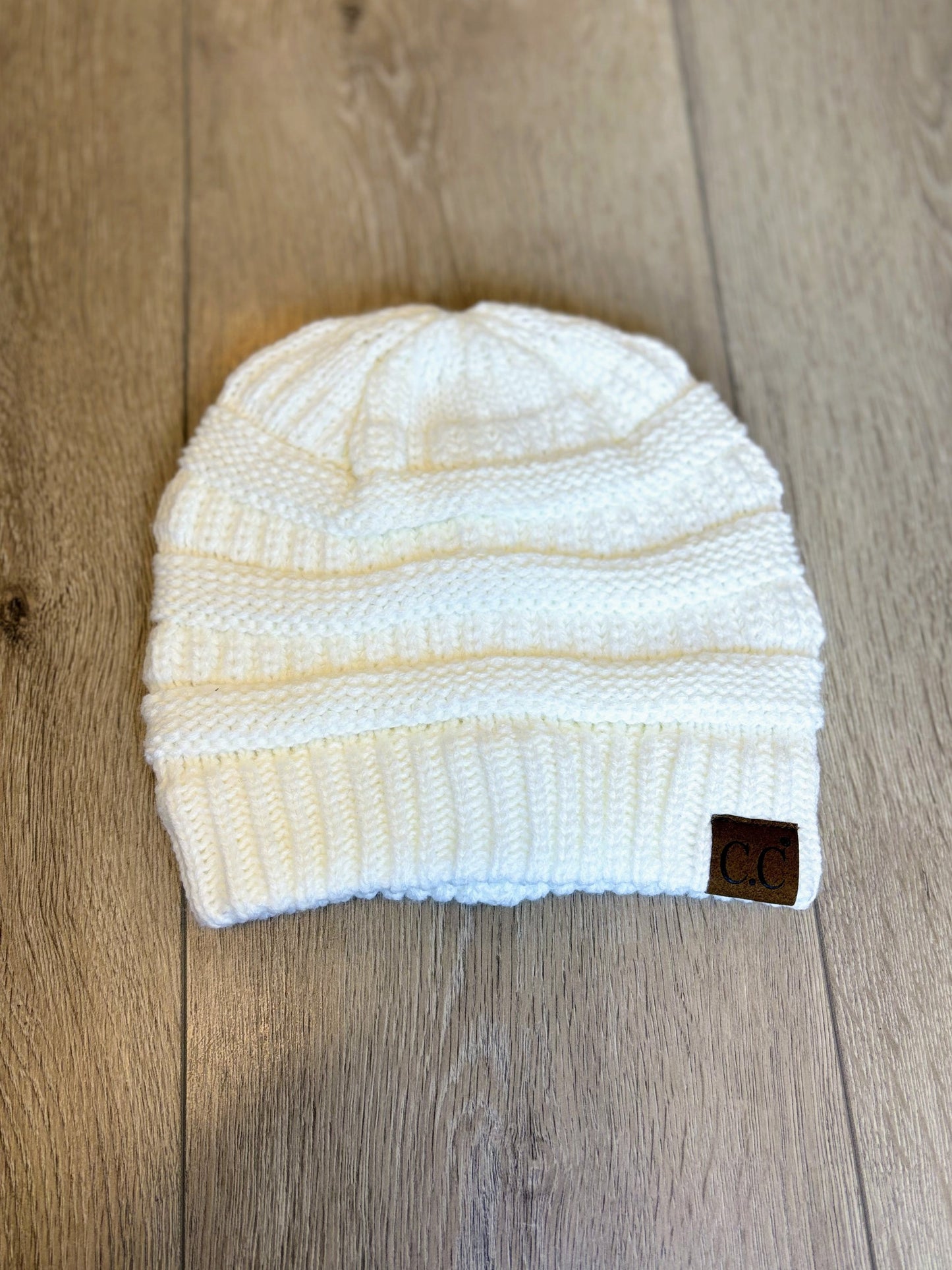 White CC knit beanie with a ribbed texture, soft material, and cozy fit, perfect for cold weather.